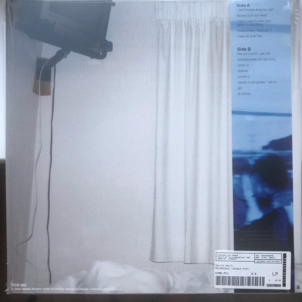 Vinyl record with a white curtain and a person on a couch in the background